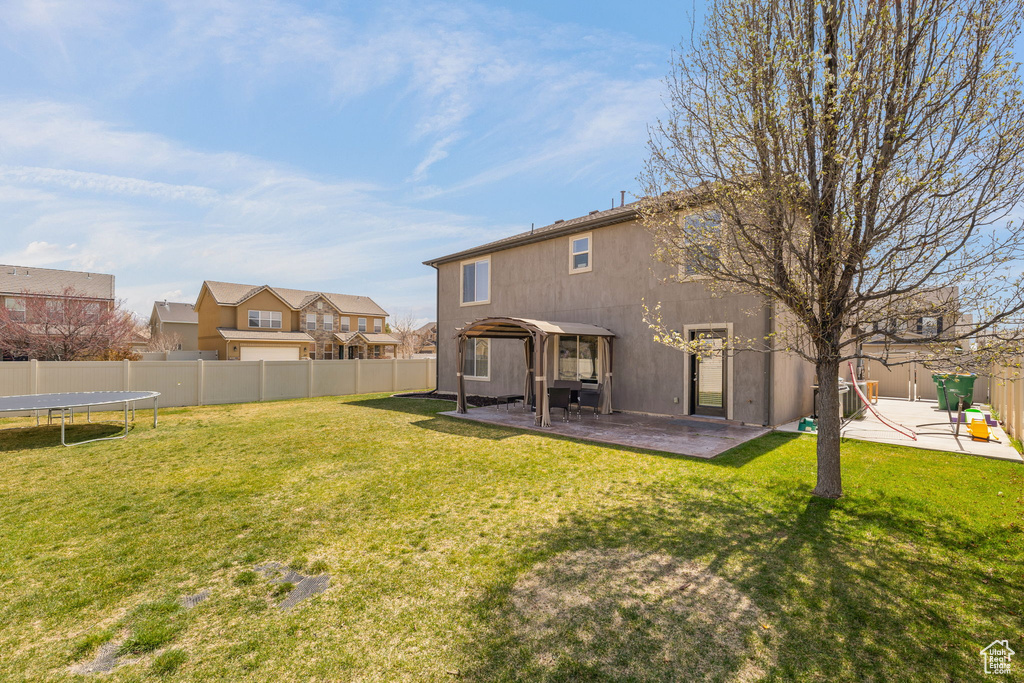 Rear view of property featuring a fenced backyard, a patio area, a trampoline, and stucco siding