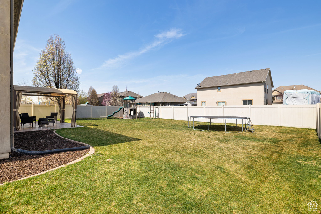 View of yard with a fenced backyard, a gazebo, a playground, a trampoline, and a patio area