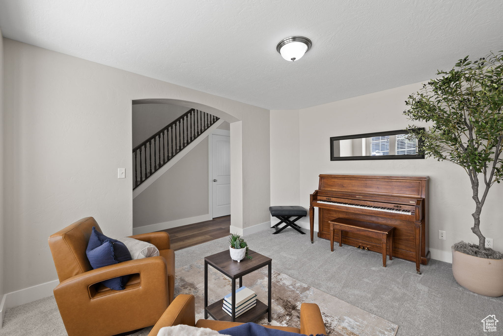 Living room with arched walkways, carpet floors, baseboards, and stairway
