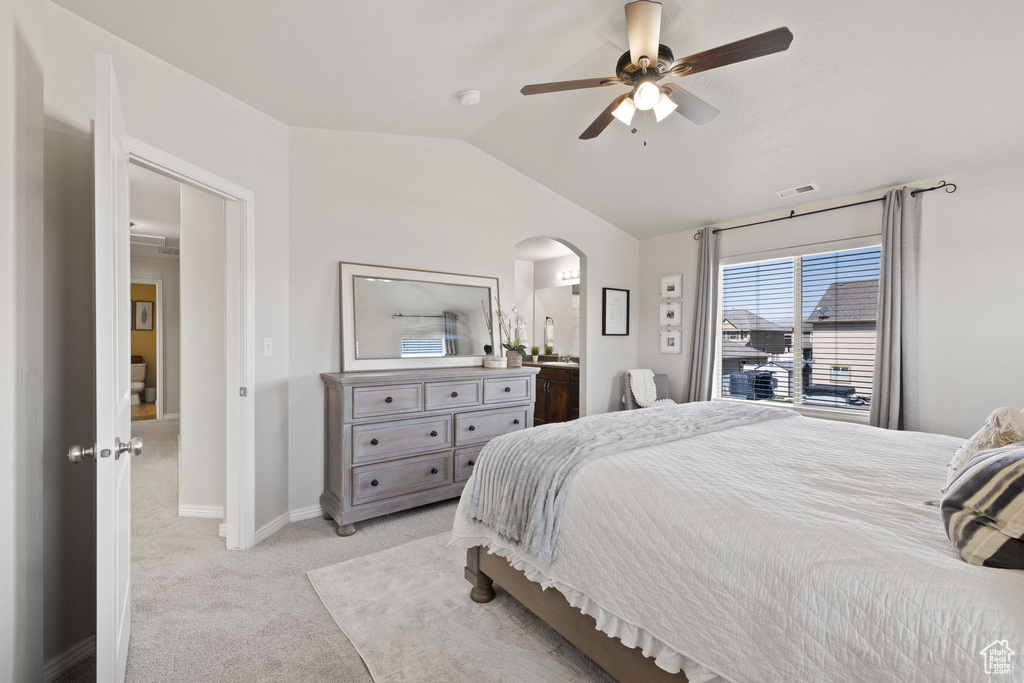Bedroom with vaulted ceiling, visible vents, arched walkways, baseboards, and light colored carpet