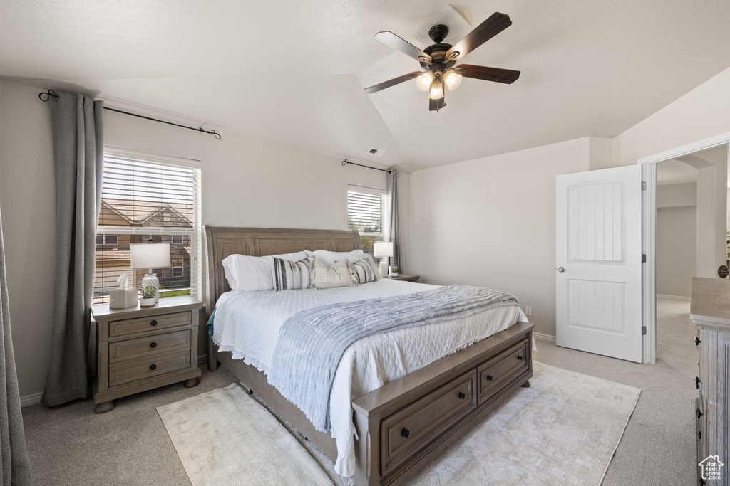Bedroom featuring vaulted ceiling, visible vents, a ceiling fan, and light carpet
