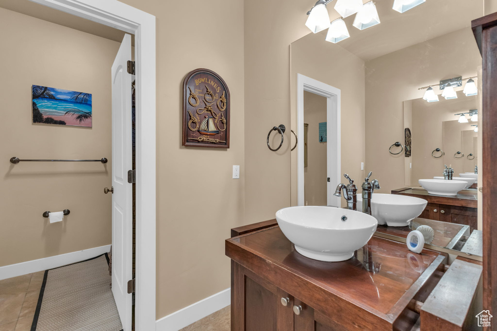 Bathroom featuring tile patterned floors, double vanity, baseboards, and a skylight
