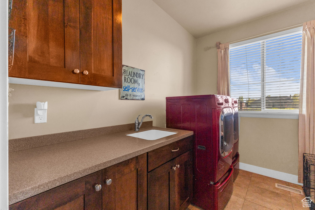 Laundry room featuring washing machine and dryer, cabinet space, baseboards, and light tile patterned floors