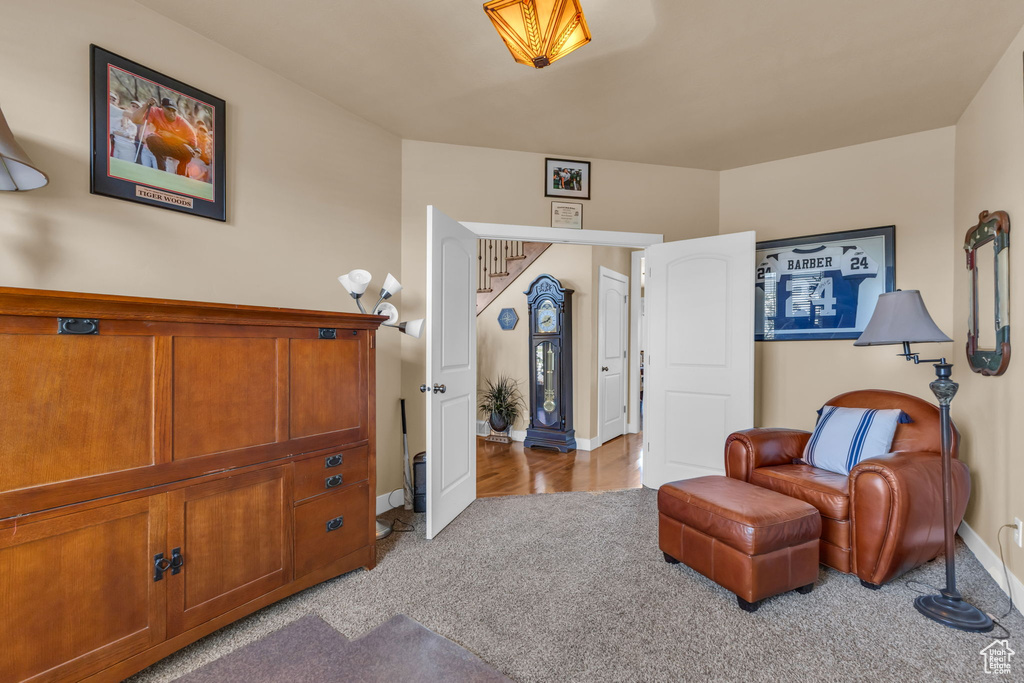 Sitting room with carpet floors, baseboards, and stairway