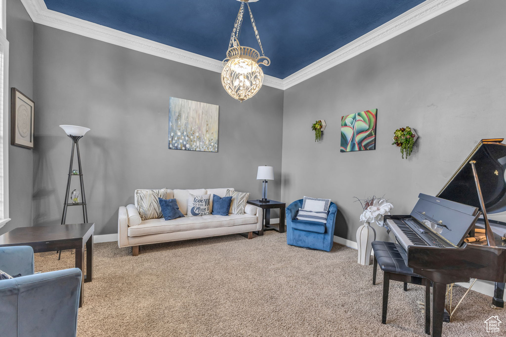 Carpeted living area featuring ornamental molding, a chandelier, and baseboards