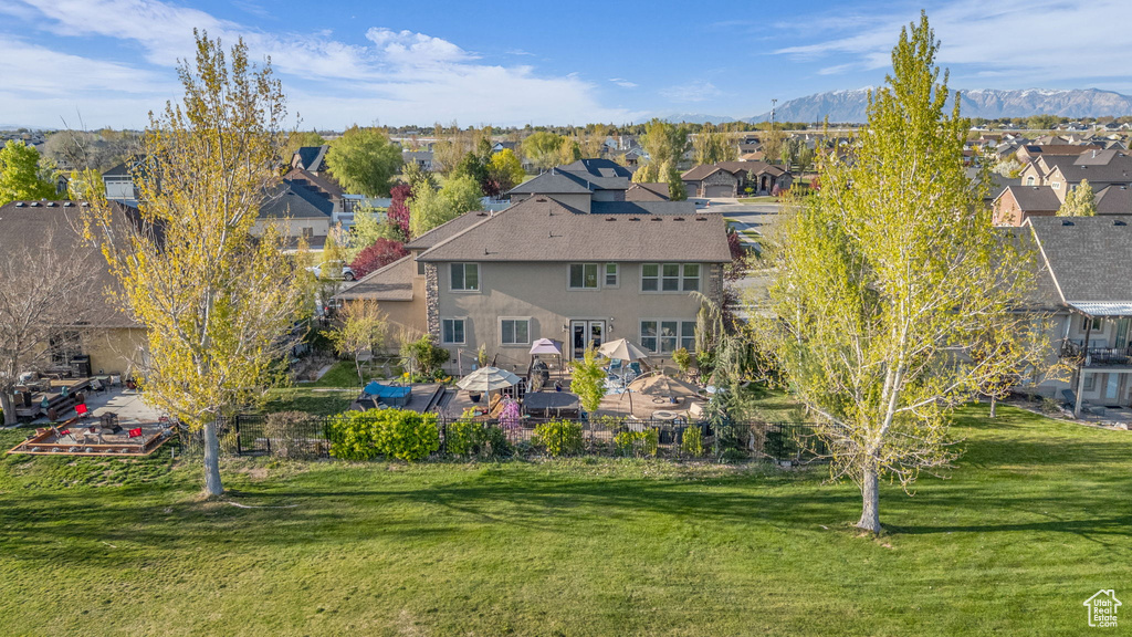 Back of house with a residential view, stucco siding, a yard, and a mountain view