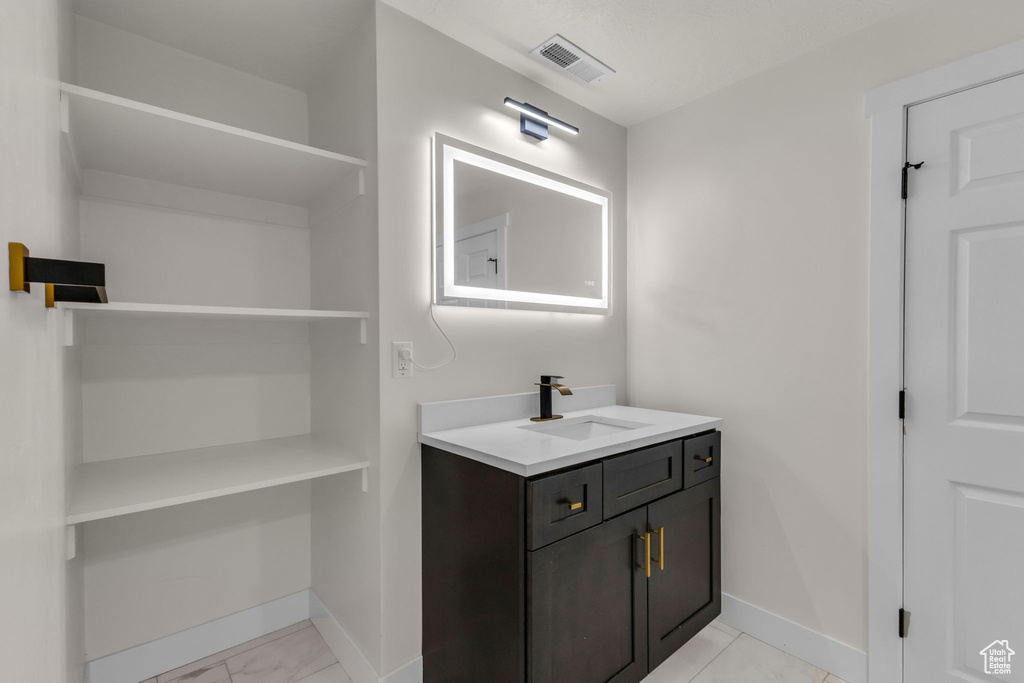 Bathroom with vanity, baseboards, and marble look tiles