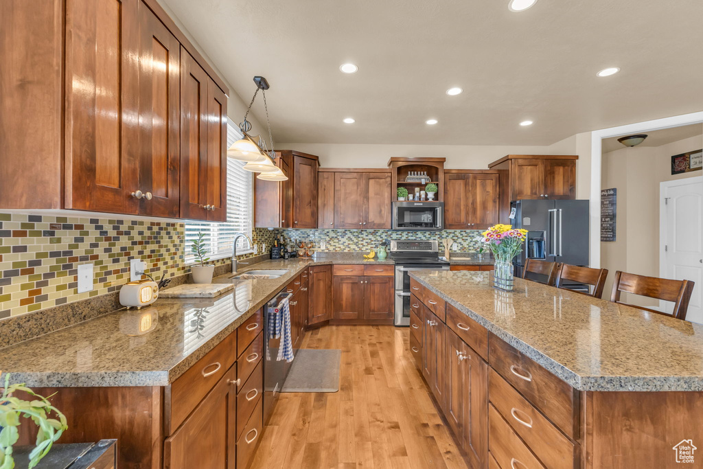 Kitchen featuring stainless steel appliances, a sink, open shelves, a center island, and light wood-style floors