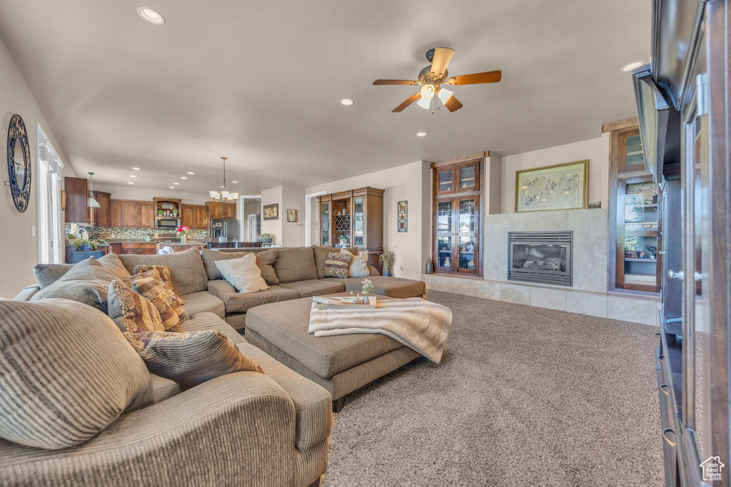Carpeted living area with recessed lighting, a ceiling fan, a fireplace, and a chandelier
