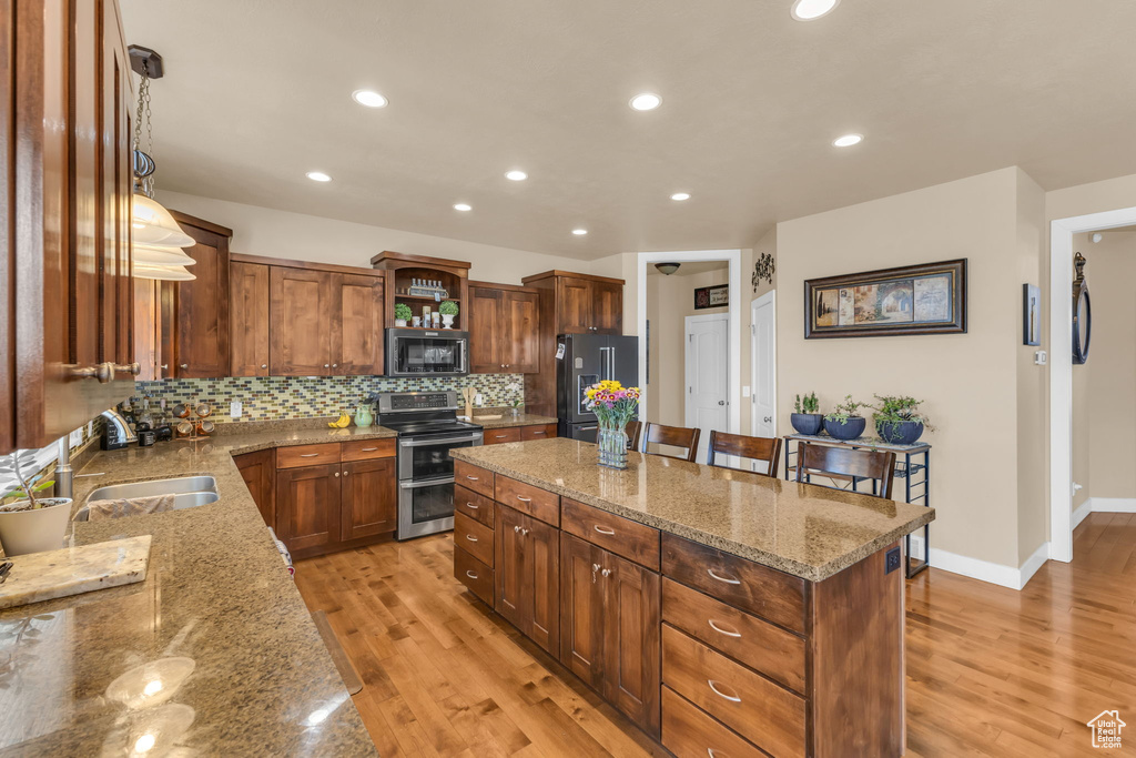 Kitchen with appliances with stainless steel finishes, a sink, a center island, light wood-style flooring, and recessed lighting