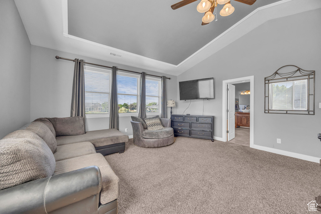 Living room featuring a ceiling fan, carpet flooring, baseboards, and lofted ceiling