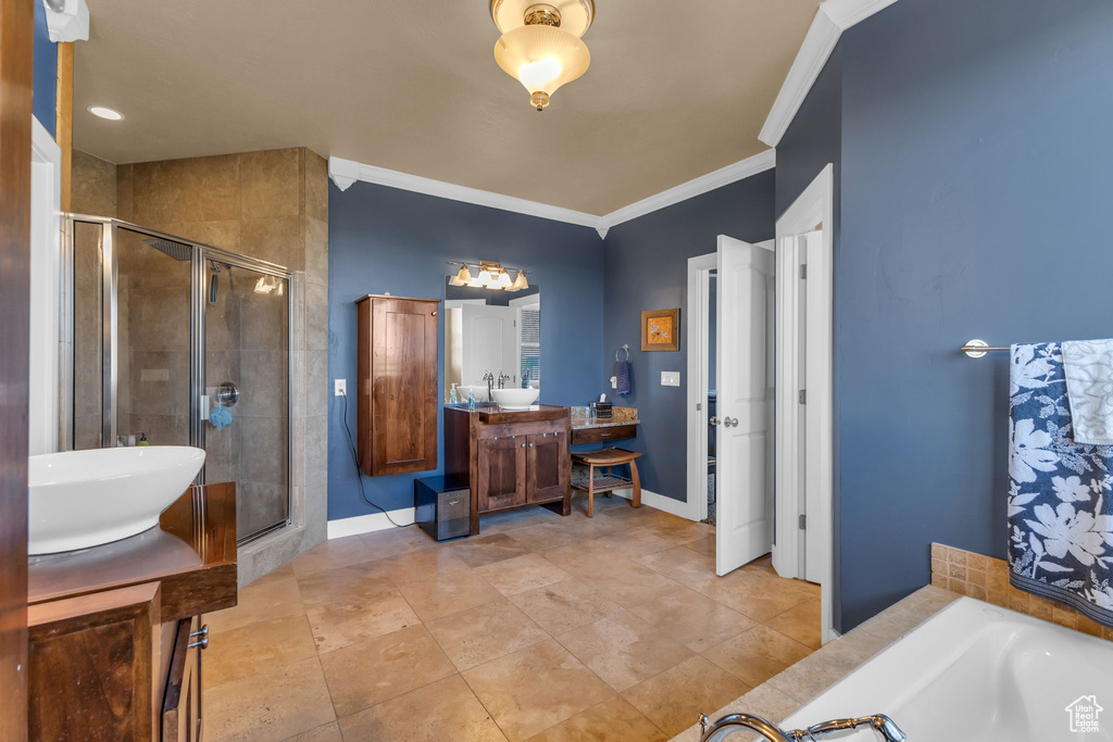 Full bath featuring vanity, a shower stall, a tub to relax in, ornamental molding, and baseboards