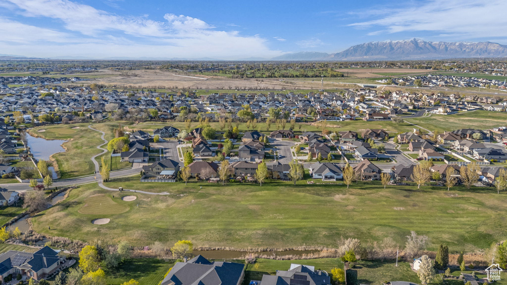 Aerial view of property and surrounding area featuring nearby suburban area, a water and mountain view, and a golf course