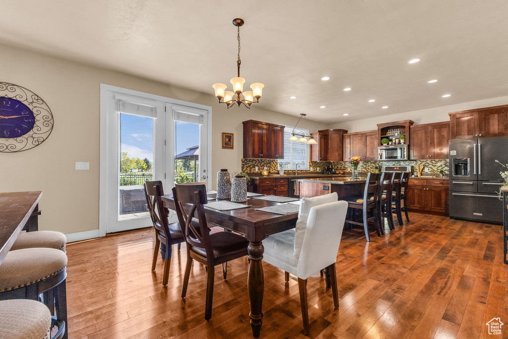 Dining space with a chandelier, dark wood-style floors, recessed lighting, baseboards, and french doors