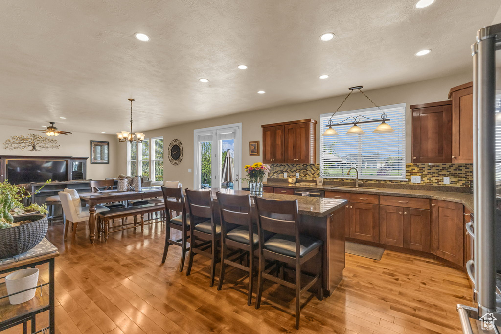 Kitchen featuring a sink, recessed lighting, tasteful backsplash, light wood-style flooring, and a kitchen bar