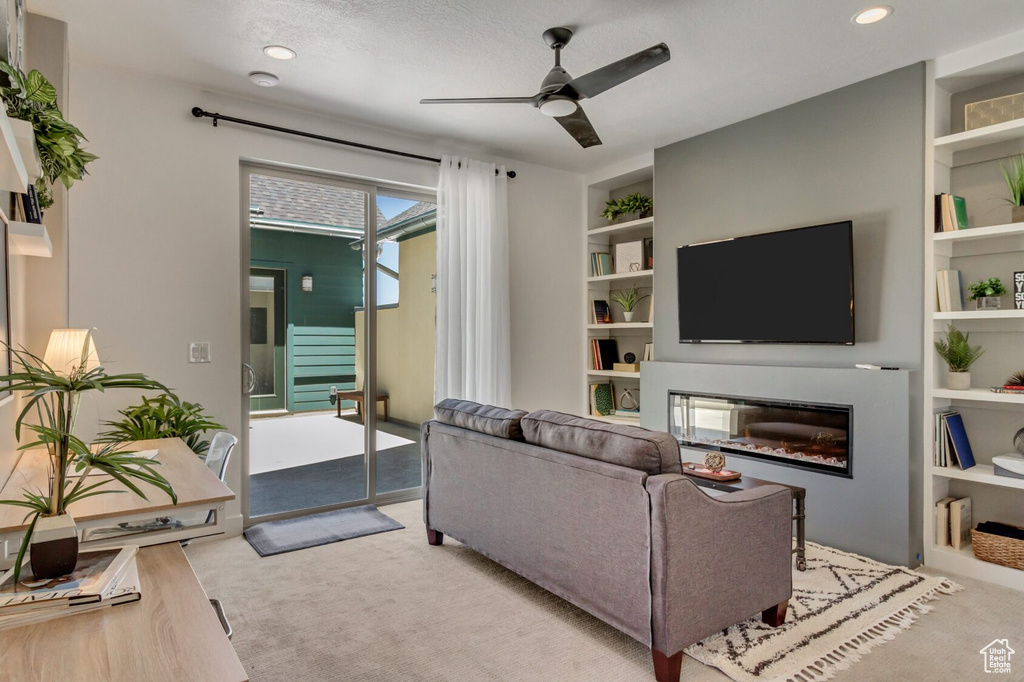 Carpeted living area featuring recessed lighting, a glass covered fireplace, built in shelves, and ceiling fan