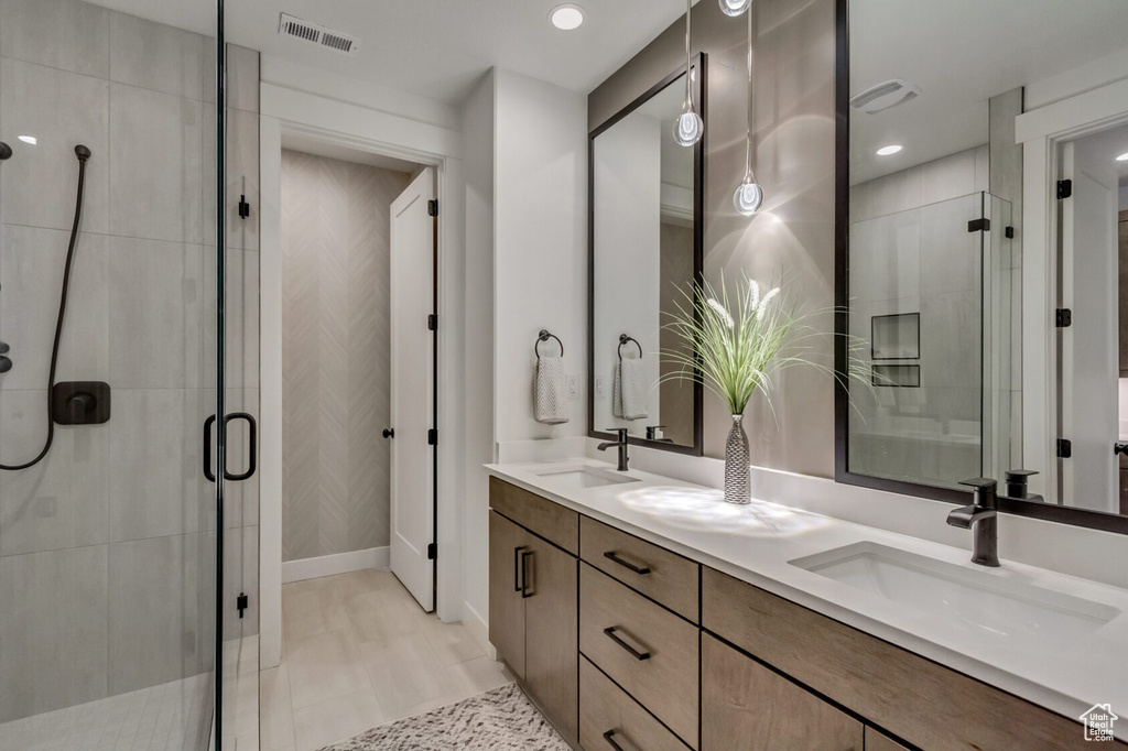 Bathroom featuring visible vents, a sink, a shower stall, and double vanity