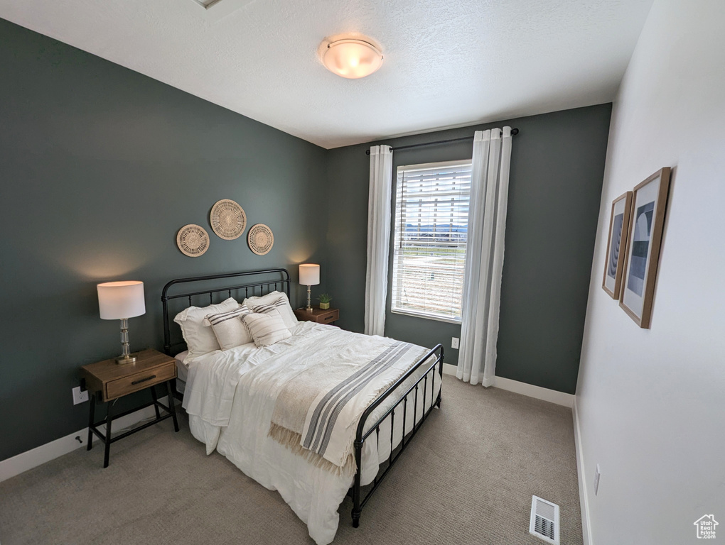 Bedroom with light carpet, baseboards, and visible vents