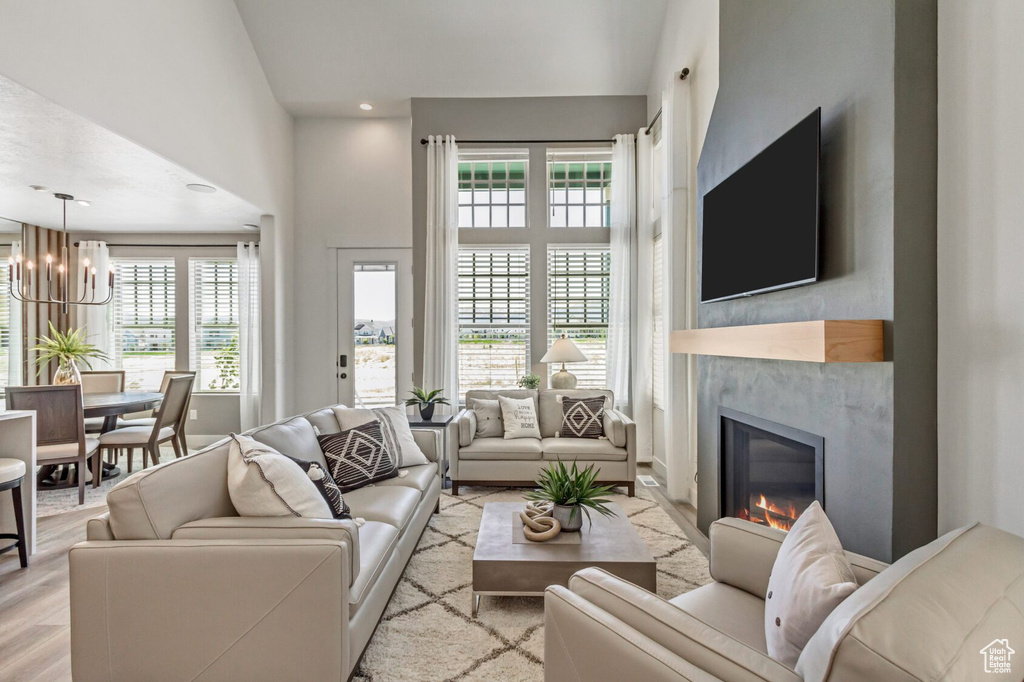 Living room featuring recessed lighting, a notable chandelier, wood finished floors, and a premium fireplace
