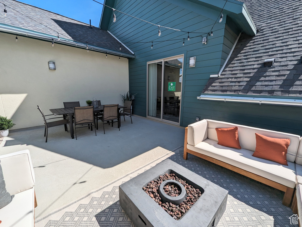 View of patio with outdoor dining area and an outdoor living space with a fire pit