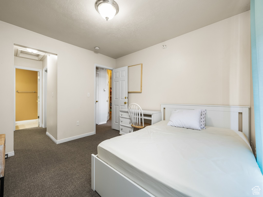 Bedroom with dark carpet, attic access, baseboards, and a textured ceiling