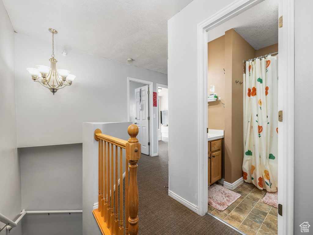 Full bathroom featuring an inviting chandelier, baseboards, a shower with curtain, and vanity