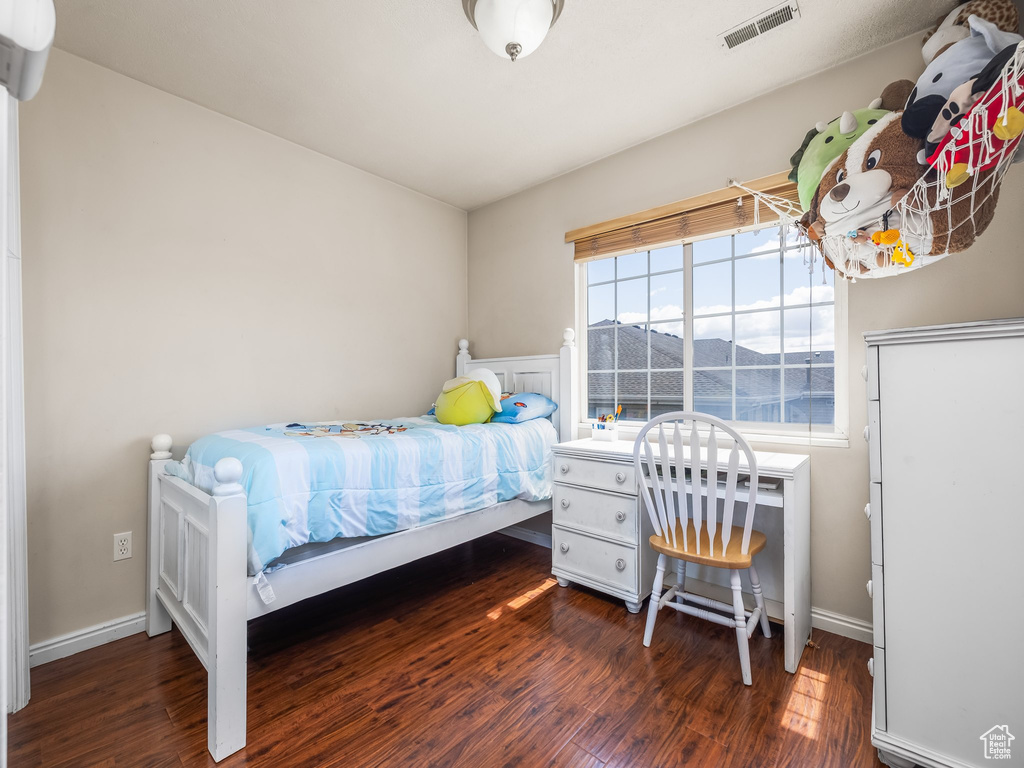 Bedroom featuring baseboards, visible vents, and wood finished floors