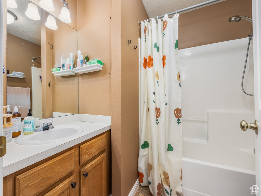 Full bathroom featuring vanity, a textured ceiling, and shower / tub combo with curtain