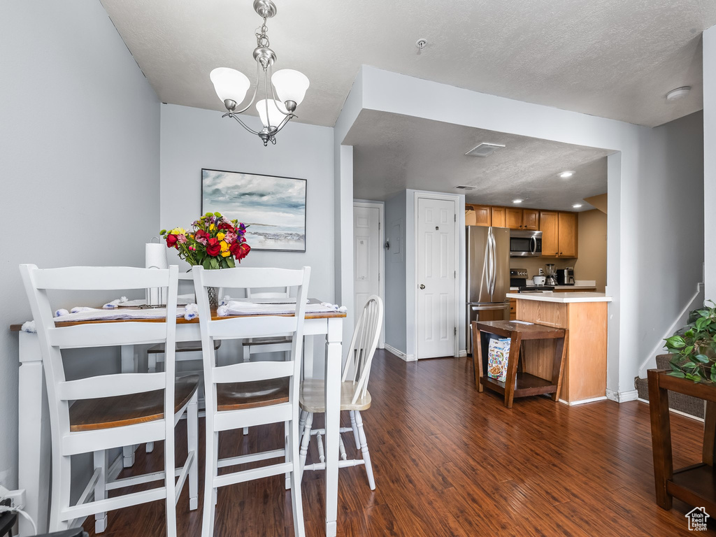 Dining room featuring baseboards, an inviting chandelier, visible vents, and dark wood-type flooring