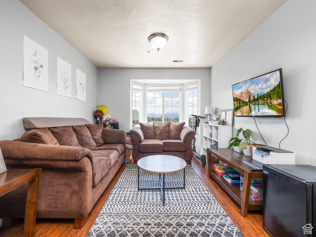 Living area featuring a textured ceiling, wood finished floors, and visible vents