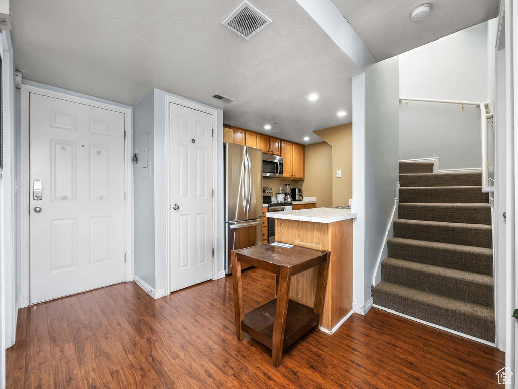 Kitchen with light countertops, stainless steel appliances, baseboards, visible vents, and dark wood-style floors