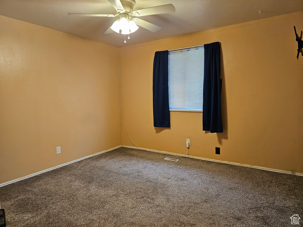 Carpeted empty room with ceiling fan and baseboards
