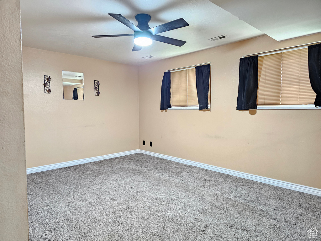Carpeted spare room with ceiling fan and baseboards