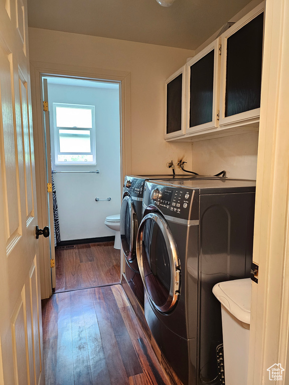 Clothes washing area with washer and dryer and dark wood-style flooring
