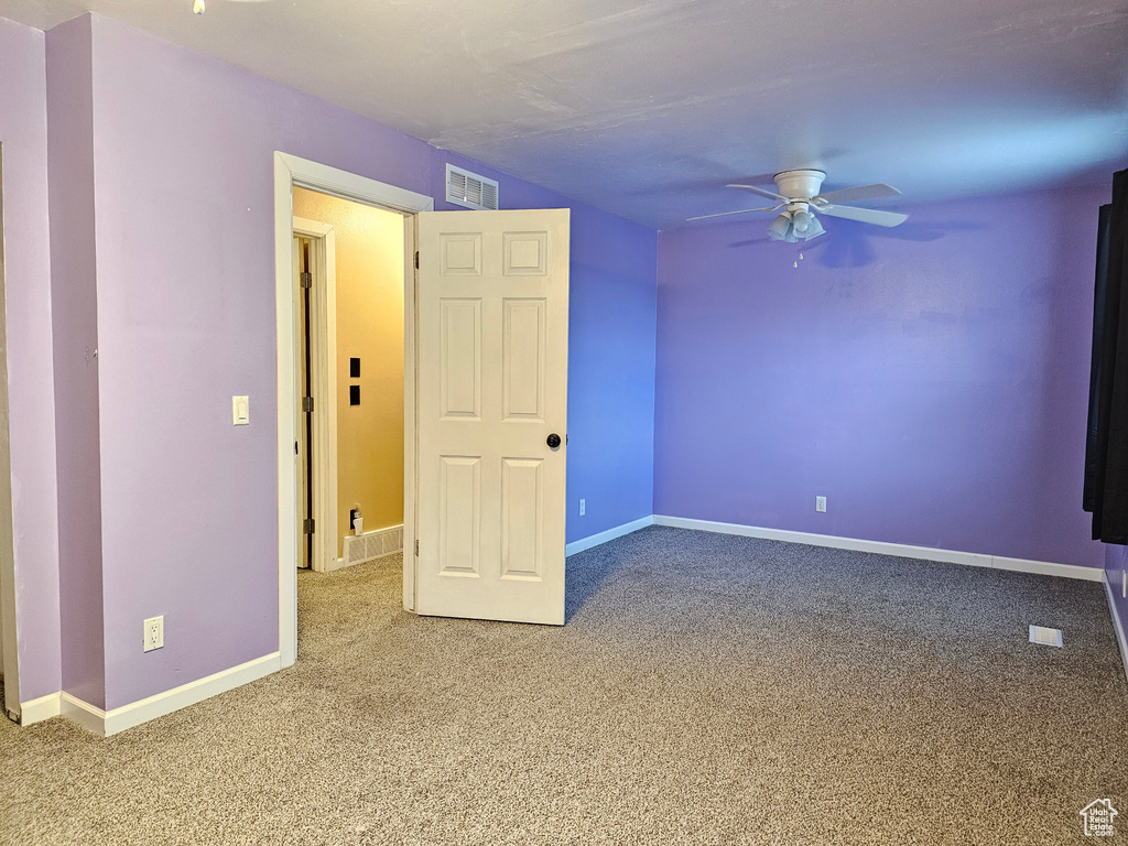 Empty room featuring carpet flooring, a ceiling fan, and baseboards