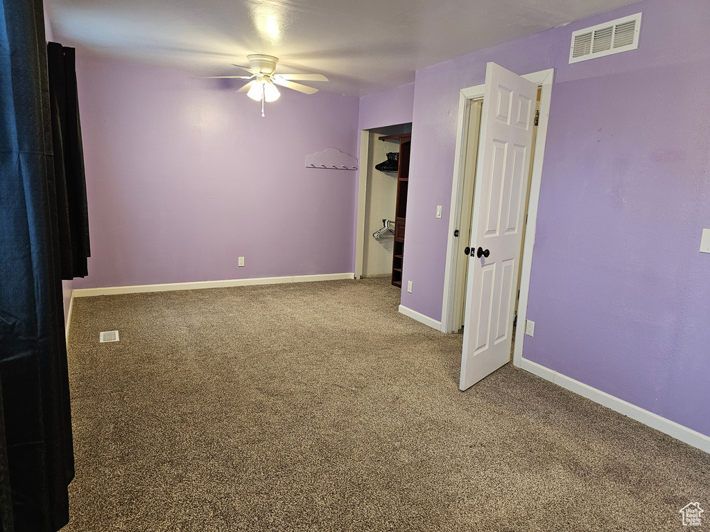 Carpeted empty room featuring a ceiling fan and baseboards