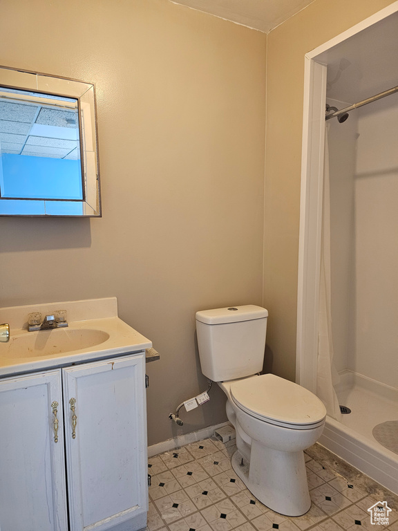 Full bath with a shower stall, vanity, toilet, baseboards, and tile patterned flooring