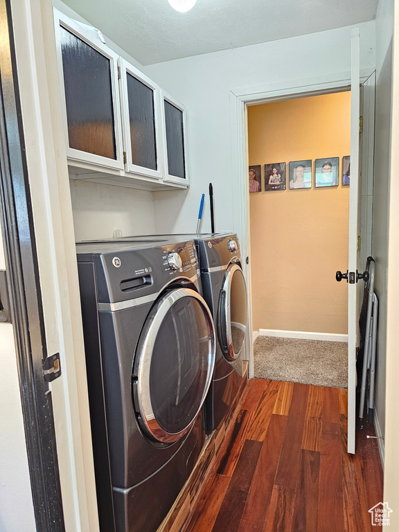 Laundry room featuring washer and dryer, cabinet space, dark wood finished floors, and baseboards