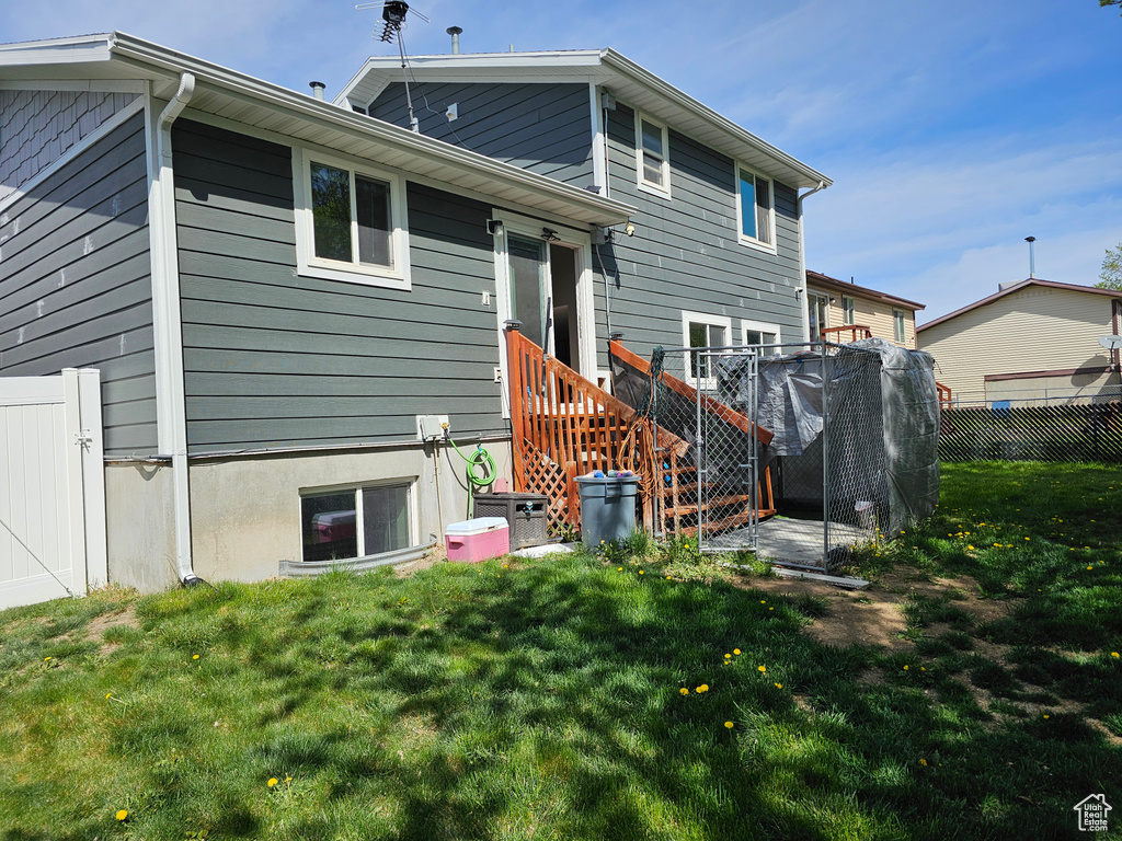 Rear view of house featuring a deck, fence, and a yard