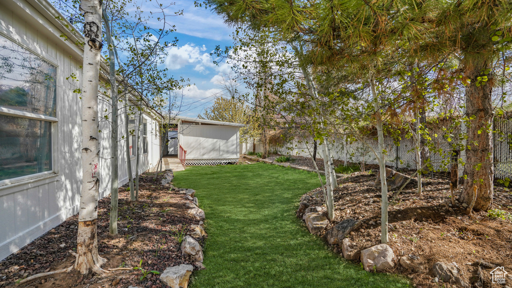 View of yard featuring a storage shed, an outbuilding, and a fenced backyard