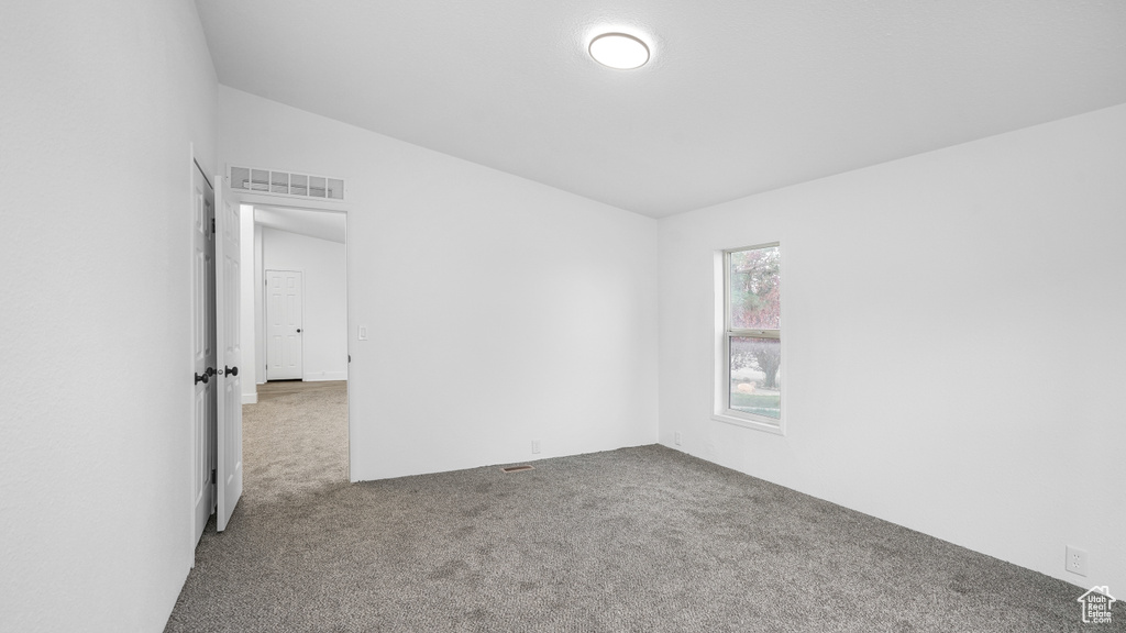 Carpeted spare room featuring lofted ceiling and visible vents