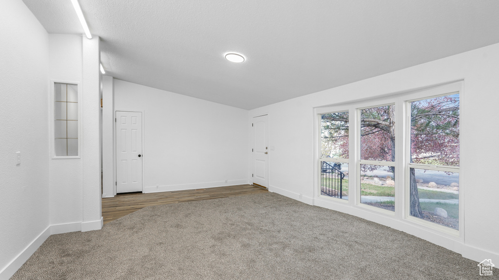 Empty room with vaulted ceiling, carpet flooring, and baseboards