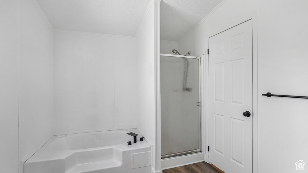Full bath with a shower stall, a garden tub, ornamental molding, and wood finished floors