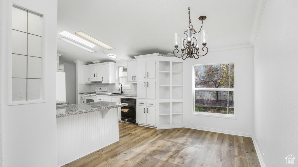 Kitchen featuring open shelves, a sink, a skylight, black dishwasher, and electric range
