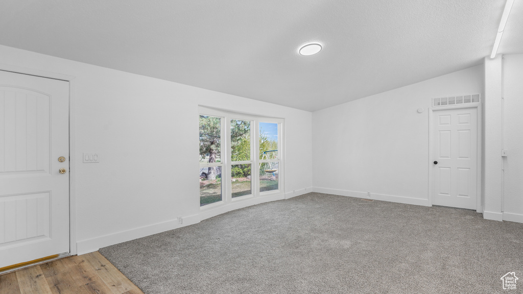 Spare room featuring lofted ceiling, baseboards, visible vents, and carpet flooring