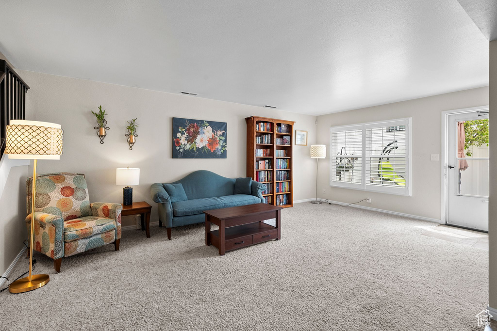 Living area with visible vents, baseboards, carpet floors, and a healthy amount of sunlight