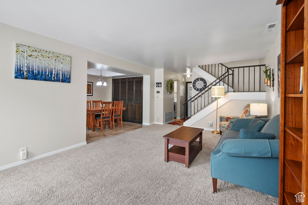 Living area featuring carpet floors, visible vents, baseboards, and stairway