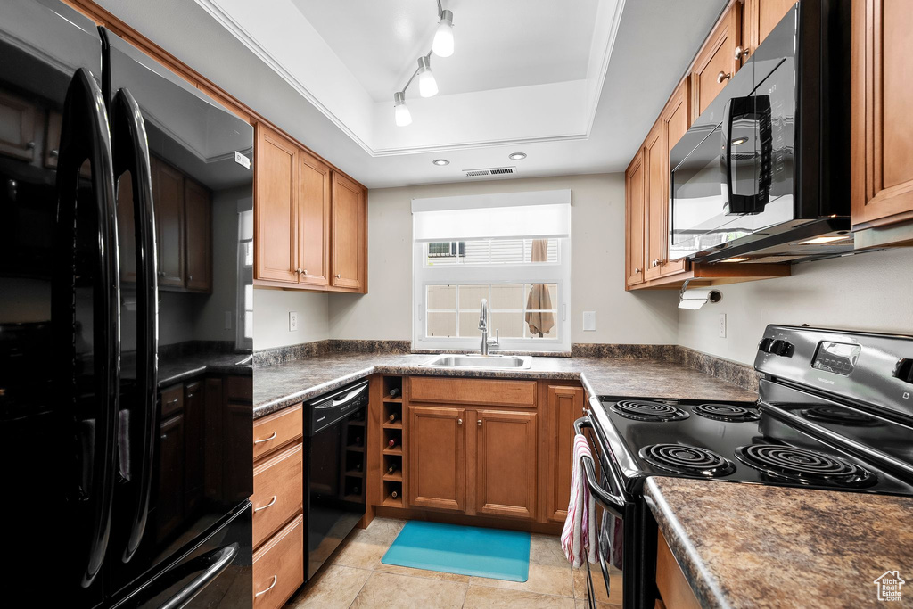 Kitchen with a tray ceiling, dark countertops, visible vents, a sink, and black appliances