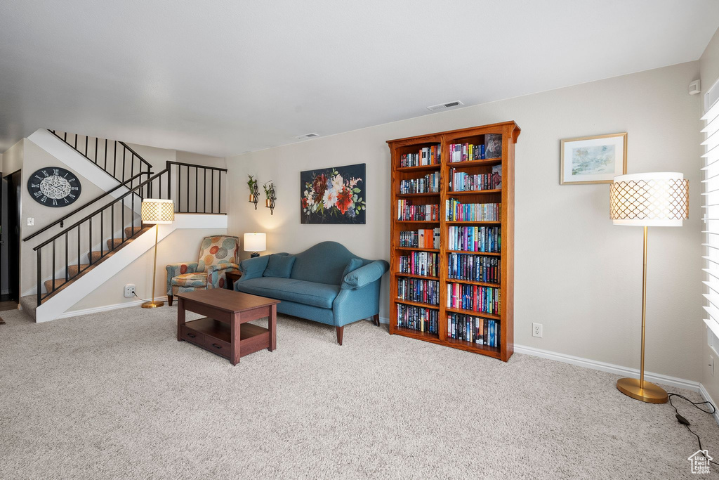 Carpeted living room with baseboards, visible vents, and stairs