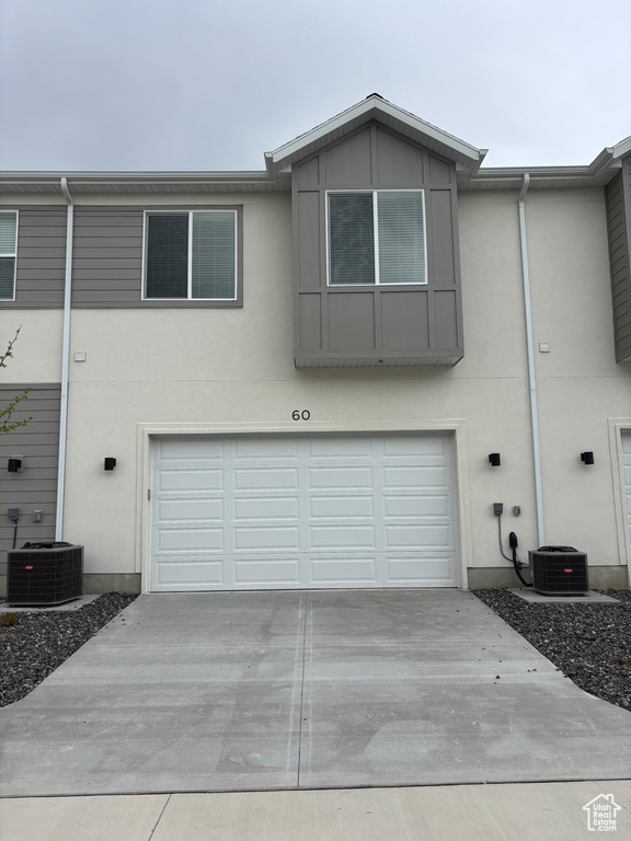 Exterior space with cooling unit, stucco siding, concrete driveway, and a garage